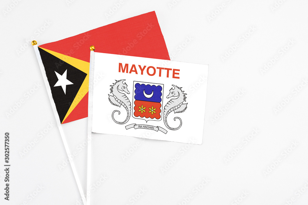 Mayotte and East Timor stick flags on white background. High quality fabric, miniature national flag. Peaceful global concept.White floor for copy space. Mayotte and East Timor stick flags on white background. High quality fabric, miniature national flag. Peaceful global concept.White floor for copy space.