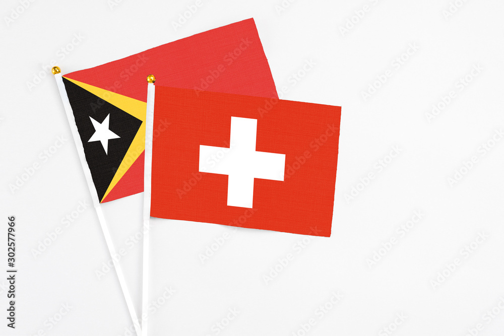 Switzerland and East Timor stick flags on white background. High quality fabric, miniature national flag. Peaceful global concept.White floor for copy space.