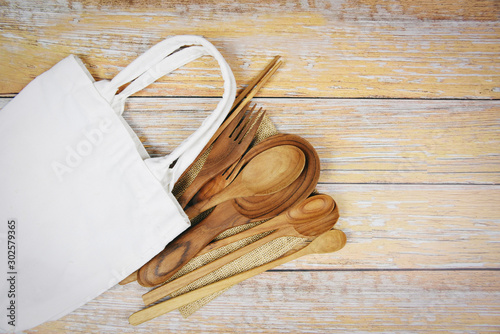 Natural kitchen tools wood products / Kitchen utensils background with spoon fork chopsticks plate cutting board object and cloth bag , top view on the table utensil wooden