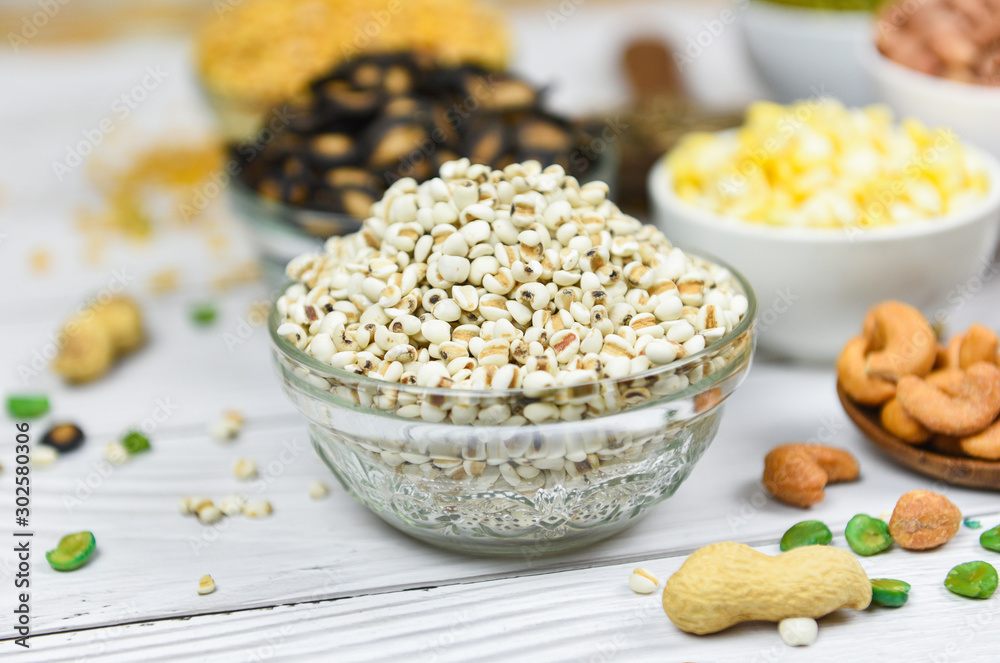 Adlay millet or pearl millet white Job's tears on bowl - Coix Lachrymal adlay jobi with different whole grains beans and legumes seeds background