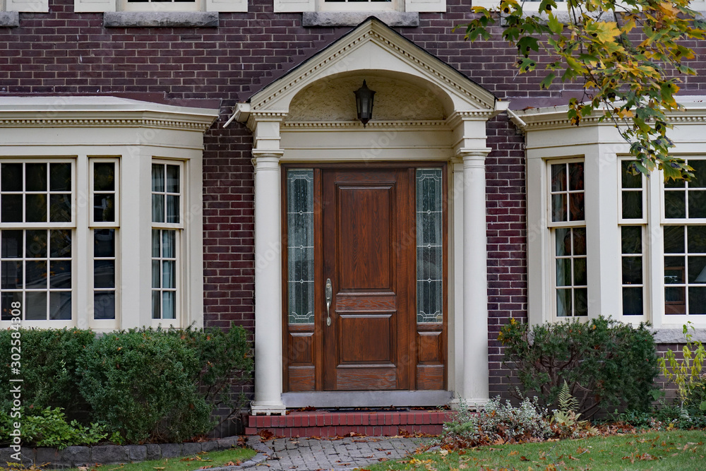 Brick house with elegant wooden front door with sidelights and portico Brick house with elegant wooden front door with sidelights and portico
