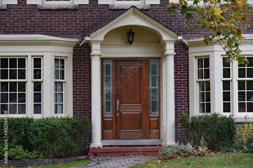 Brick house with elegant wooden front door with sidelights and portico