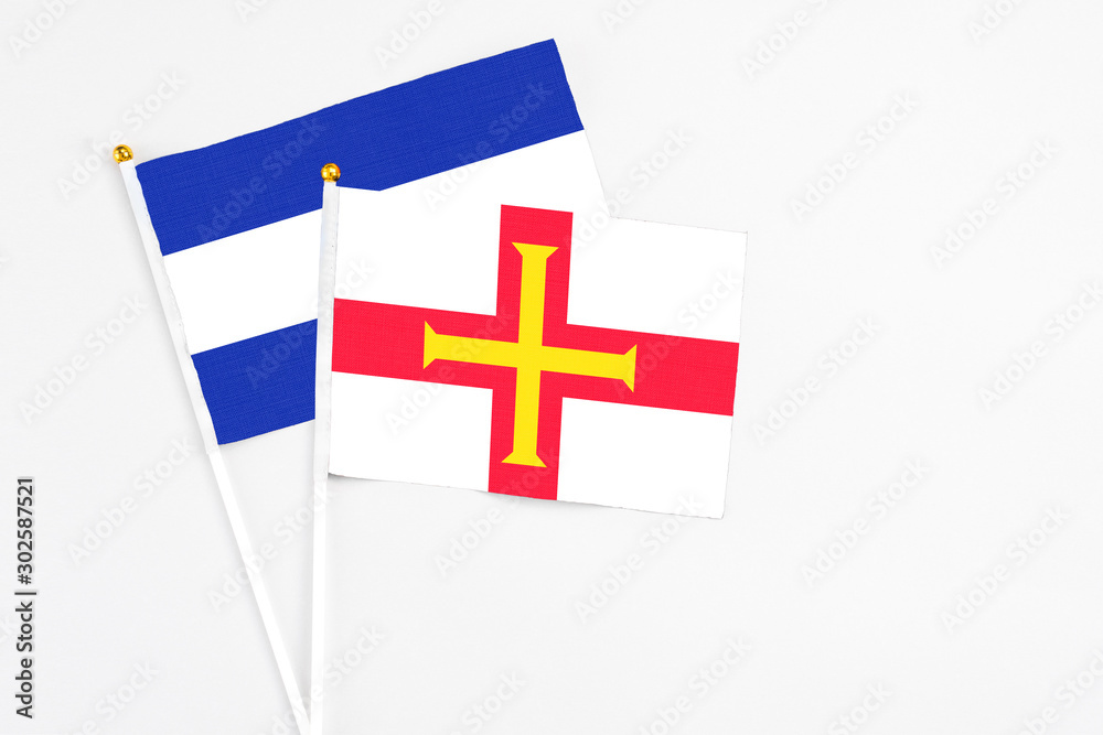 Guernsey and El Salvador stick flags on white background. High quality fabric, miniature national flag. Peaceful global concept.White floor for copy space.