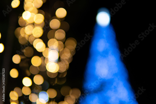 Christmas tree with golden twinkling lights Bokeh. Snowflake on bright Background.Beautiful Night light in the City on Chrismas.Xmas golden decoration. Happy New Year black background.