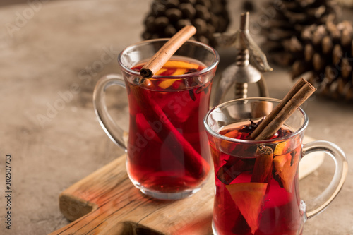 Two glasses of christmas mulled wine with oranges and spices on a textural background. Selective focus. Copy space.
