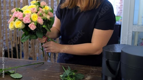 Floral business concept. Woman florist creating making flowers bunch bouquet from different sorts of roses over table in flower shop, hands closeup. Working day in floristic studo store salon.