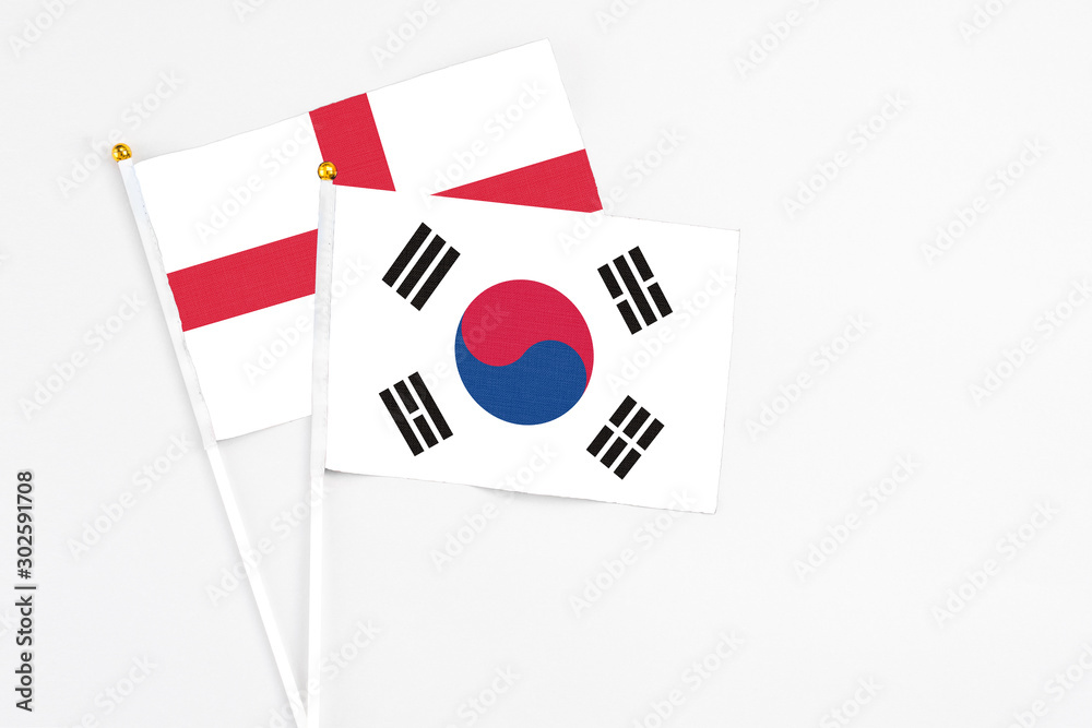 South Korea and England stick flags on white background. High quality fabric, miniature national flag. Peaceful global concept.White floor for copy space.