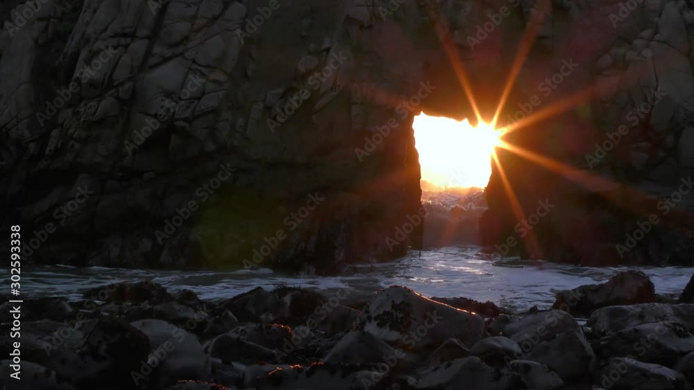 Amazing sunstar against a keyhole rock on the ocean provides a religious and moving experience as the sun rays and sunlight pierce through the geological formation Amazing sunstar against a keyhole rock on the ocean provides a religious and moving experience as the sun rays and sunlight pierce through the geological formation