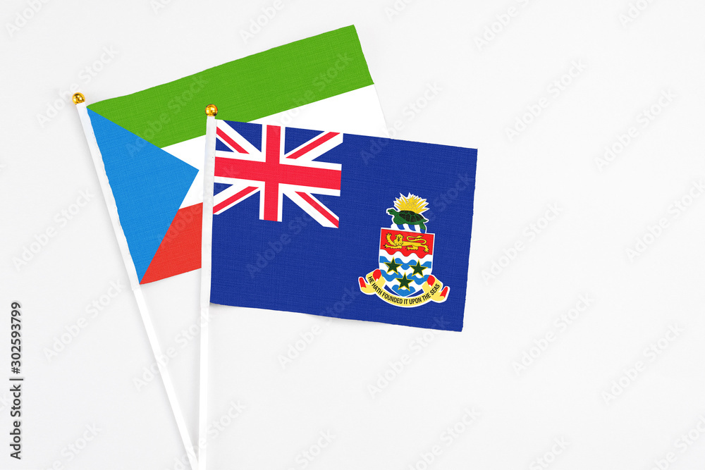 Fototapeta premium Cayman Islands and Equatorial Guinea stick flags on white background. High quality fabric, miniature national flag. Peaceful global concept.White floor for copy space.