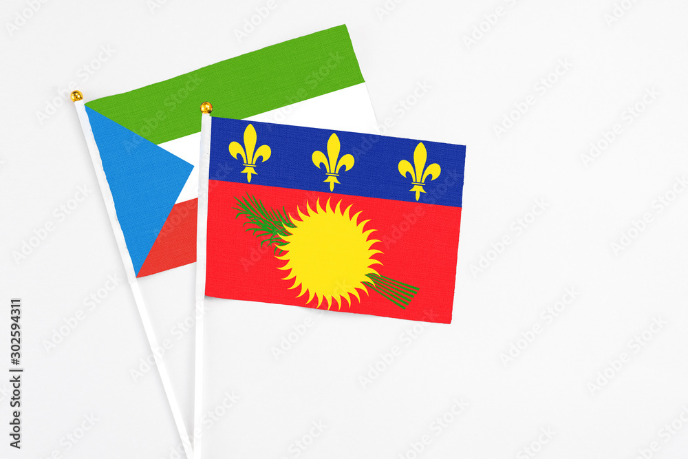 Guadeloupe and Equatorial Guinea stick flags on white background. High quality fabric, miniature national flag. Peaceful global concept.White floor for copy space.
