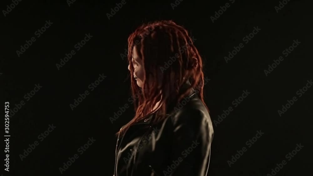 concept dances, parties, advertising leather jackets, styling hair, hairdressing dreadlocks, make-up: dark lipstick. rocker dancing on black background, woman styling red hair concept dances, parties, advertising leather jackets, styling hair, hairdressing dreadlocks, make-up: dark lipstick. rocker dancing on black background, woman styling red hair