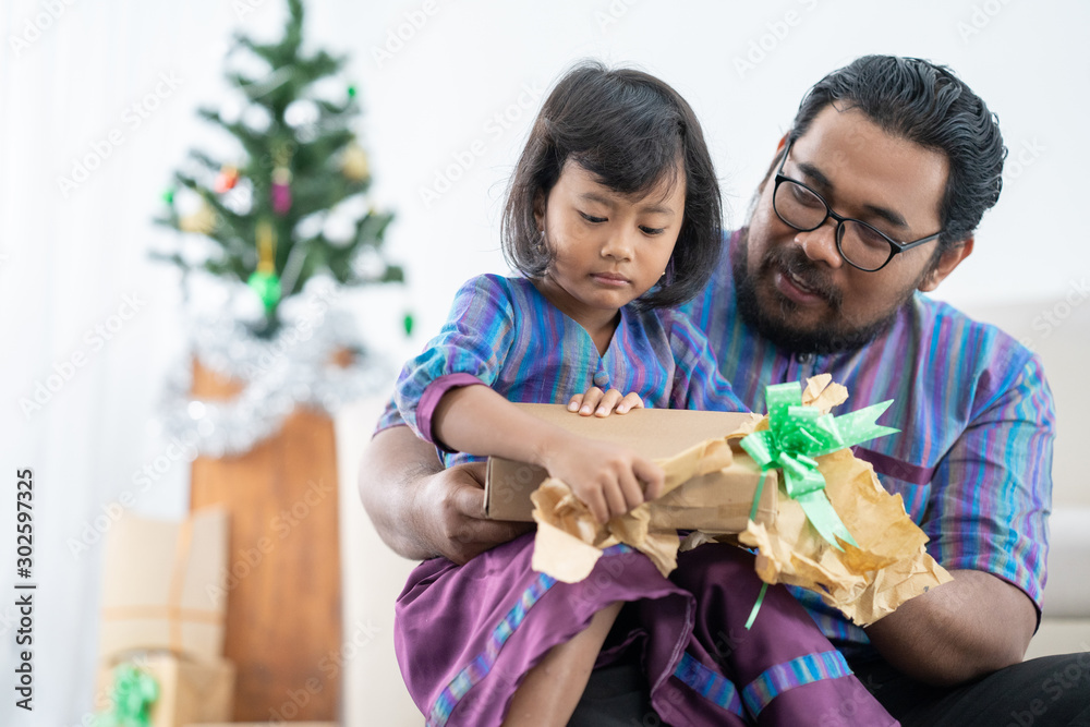 father and daughter sitting together and open the present in christmast day father and daughter sitting together and open the present in christmast day