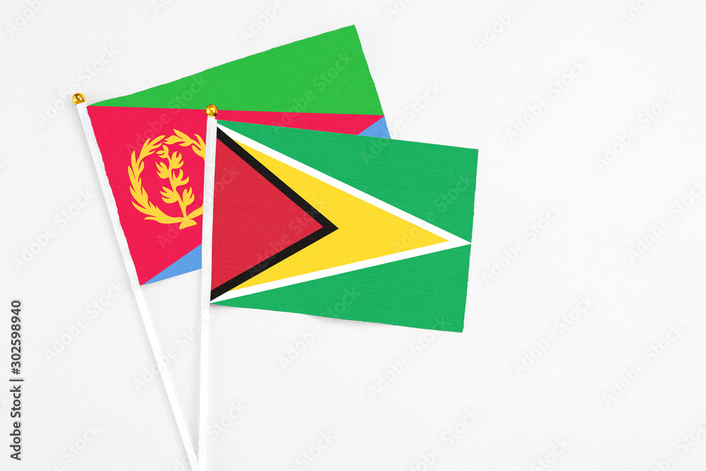 Guyana and Eritrea stick flags on white background. High quality fabric, miniature national flag. Peaceful global concept.White floor for copy space.