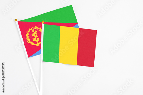 Mali and Eritrea stick flags on white background. High quality fabric, miniature national flag. Peaceful global concept.White floor for copy space.