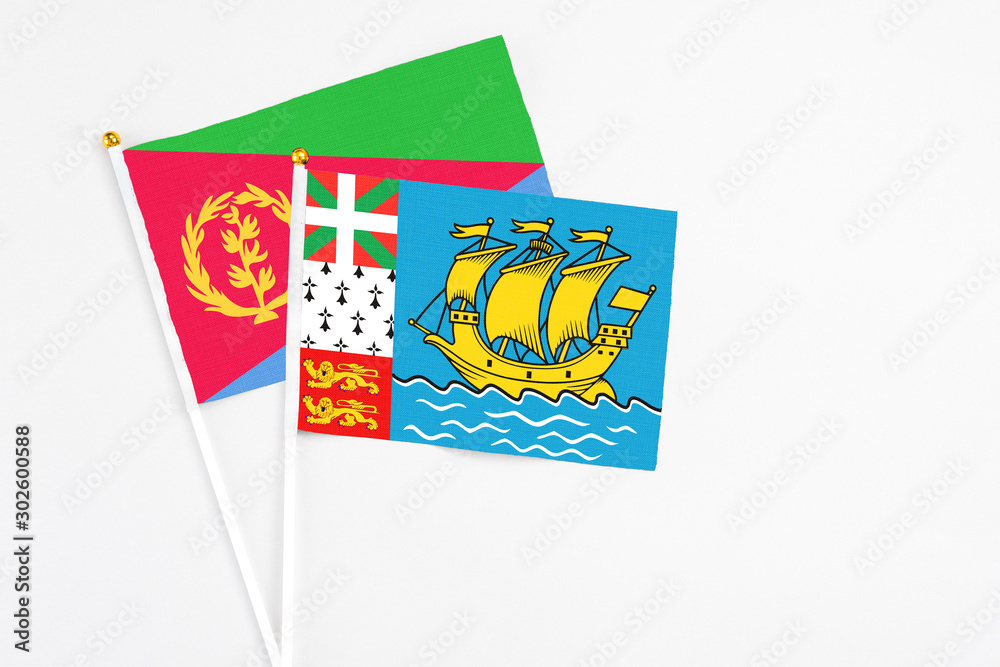 Obraz premium Saint Pierre And Miquelon and Eritrea stick flags on white background. High quality fabric, miniature national flag. Peaceful global concept.White floor for copy space.