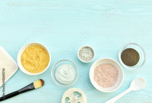 Pink, green, yellow and black cosmetic clay in bowls, natural skin care, flat lay with copy space.