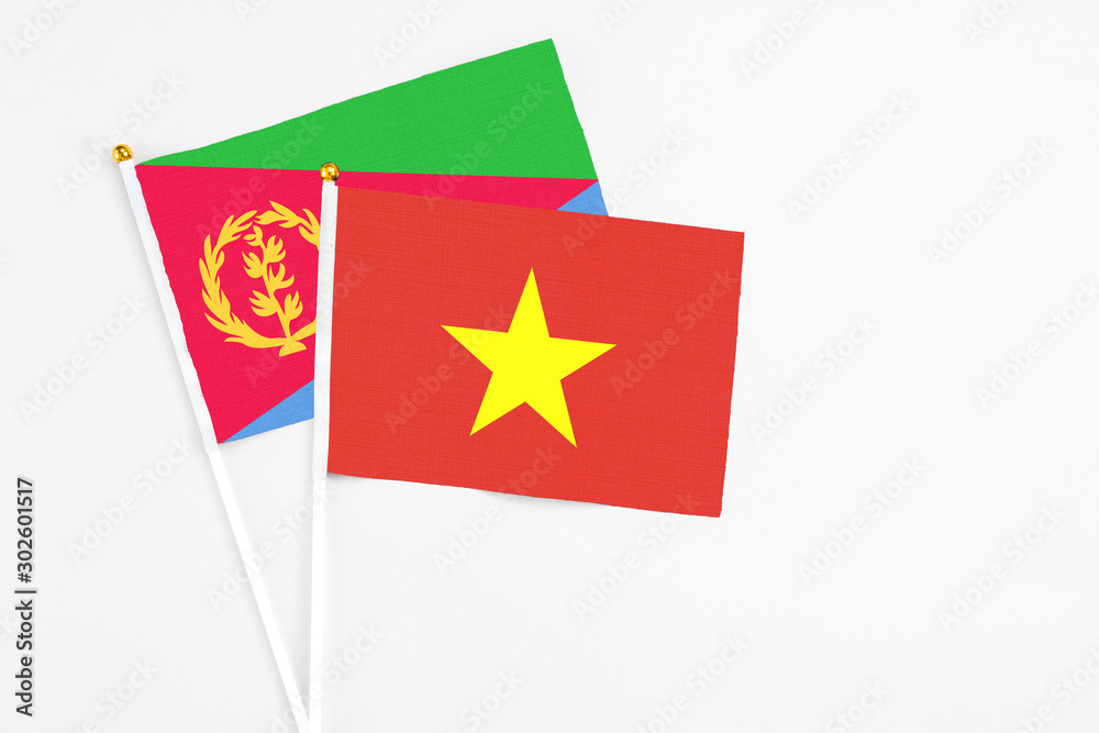 Vietnam and Eritrea stick flags on white background. High quality fabric, miniature national flag. Peaceful global concept.White floor for copy space. Vietnam and Eritrea stick flags on white background. High quality fabric, miniature national flag. Peaceful global concept.White floor for copy space.
