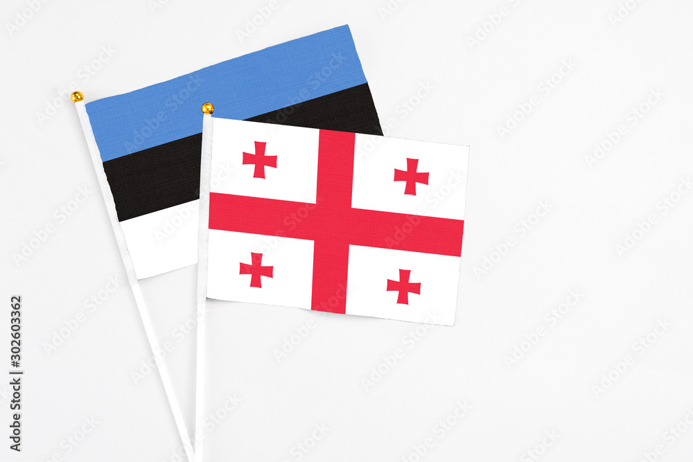 Georgia and Estonia stick flags on white background. High quality fabric, miniature national flag. Peaceful global concept.White floor for copy space.
