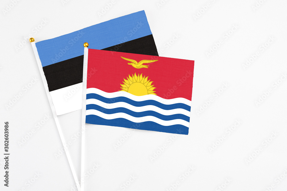 Naklejka premium Kiribati and Estonia stick flags on white background. High quality fabric, miniature national flag. Peaceful global concept.White floor for copy space.