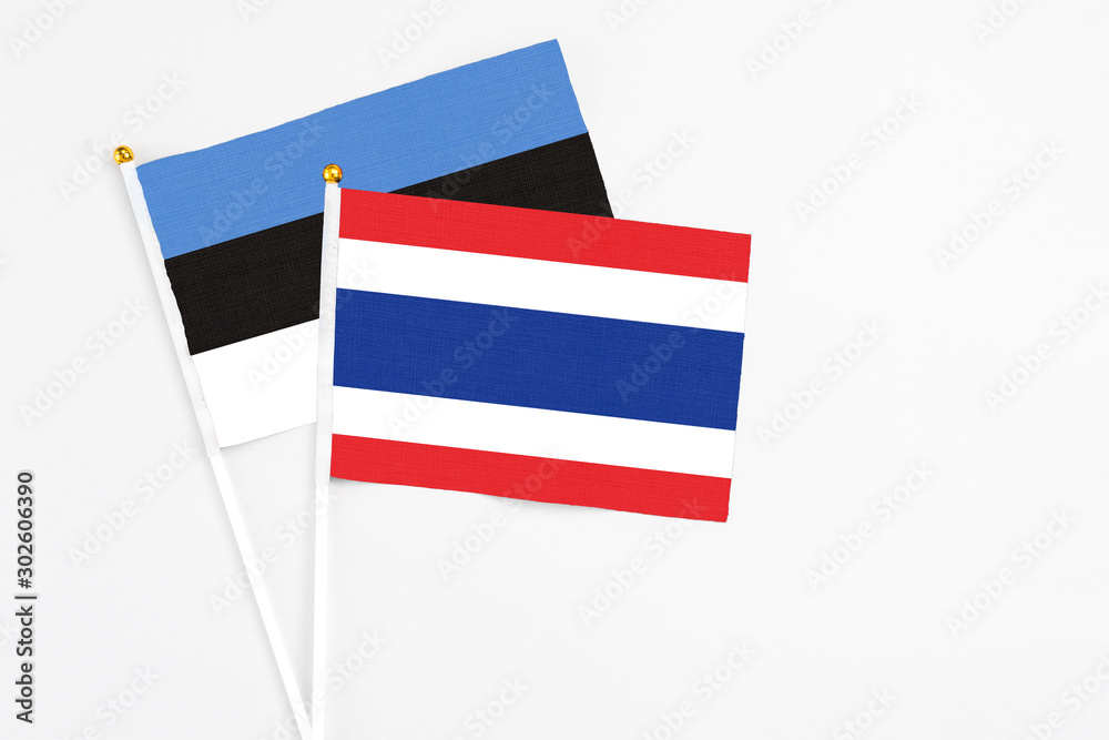 Thailand and Estonia stick flags on white background. High quality fabric, miniature national flag. Peaceful global concept.White floor for copy space.