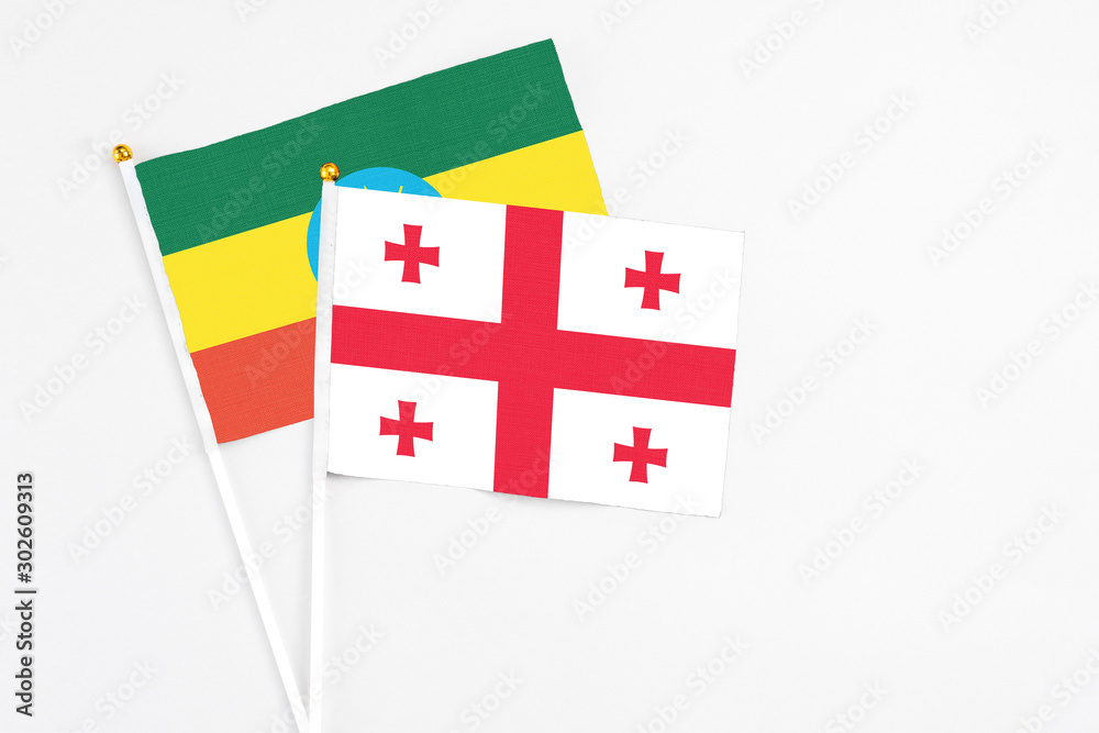 Georgia and Ethiopia stick flags on white background. High quality fabric, miniature national flag. Peaceful global concept.White floor for copy space.