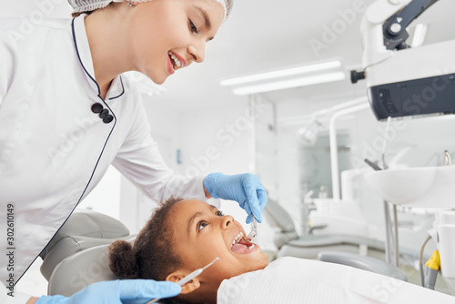 Dentist treating teeth of little african girl.