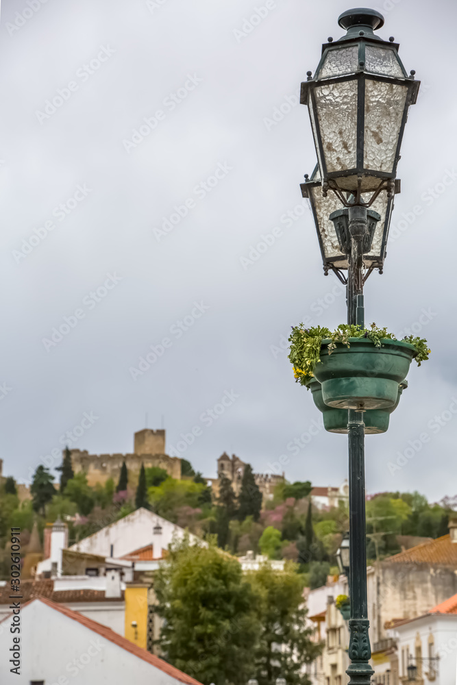 View of a classic lamp post in Tomar city downtown, with Convent of Christ building as background