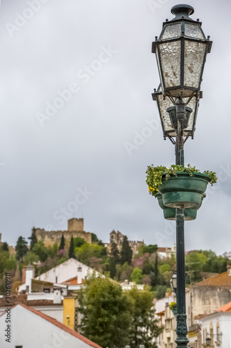 View of a classic lamp post in Tomar city downtown, with Convent of Christ building as background © Miguel Almeida