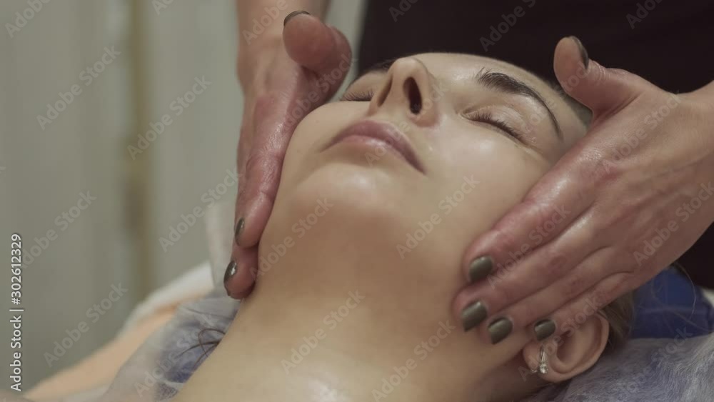 Woman is having cosmetic treatment at spa salon. Cosmetologist medical anti age face lifting massage. facial cleansing with professional cosmetic facial massage. Applying the mask to the face. Woman is having cosmetic treatment at spa salon. Cosmetologist medical anti age face lifting massage. facial cleansing with professional cosmetic facial massage. Applying the mask to the face.