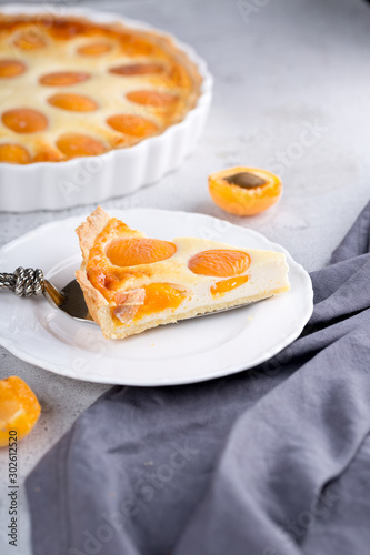 Apricot and cottage cheese pie or shortbread crust cake in white baking pan on dark grey washed linen table cloth, summer fruit dessert 