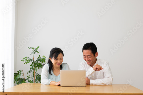 パソコンを一緒に操作する夫婦