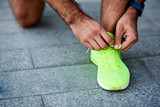Man tying running shoes on the street.