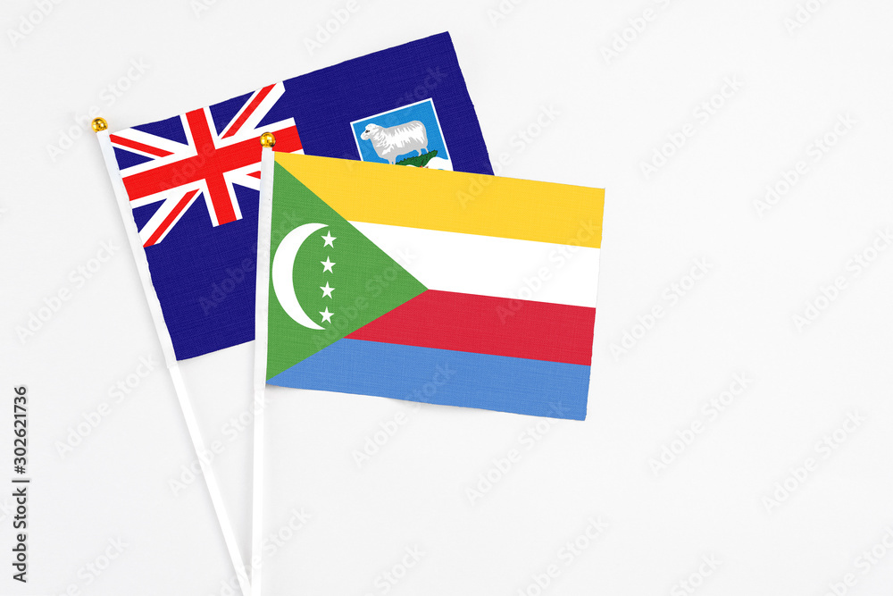 Comoros and Falkland Islands stick flags on white background. High quality fabric, miniature national flag. Peaceful global concept.White floor for copy space. Comoros and Falkland Islands stick flags on white background. High quality fabric, miniature national flag. Peaceful global concept.White floor for copy space.