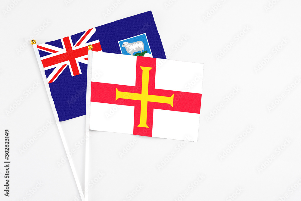Guernsey and Falkland Islands stick flags on white background. High quality fabric, miniature national flag. Peaceful global concept.White floor for copy space.