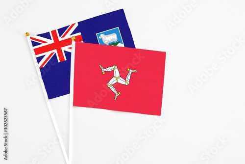 Isle Of Man and Falkland Islands stick flags on white background. High quality fabric, miniature national flag. Peaceful global concept.White floor for copy space.