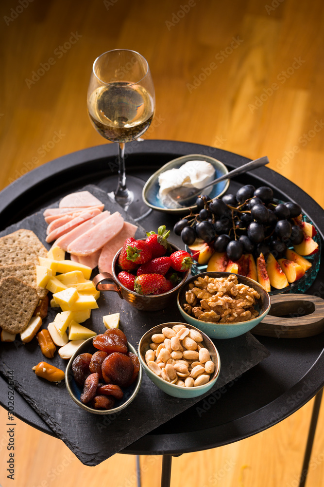 Cheese and fruits plate with glass of white wine on round tray, colorful  and delicious charcuterie with snacks and wineglass for romantic evening, wine  tasting, selective focus. Stock Photo | Adobe Stock