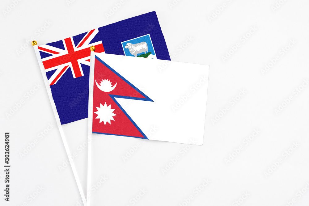 Fototapeta premium Nepal and Falkland Islands stick flags on white background. High quality fabric, miniature national flag. Peaceful global concept.White floor for copy space.
