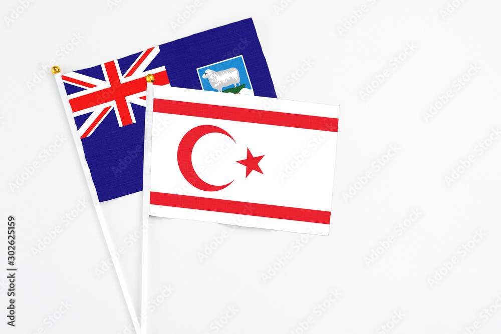 Fototapeta premium Northern Cyprus and Falkland Islands stick flags on white background. High quality fabric, miniature national flag. Peaceful global concept.White floor for copy space.