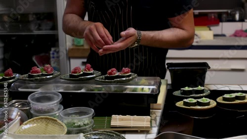 Sushi chef's work station, during preparation and plating of a fine dining sushi dinner. Close up on the delicate handwork.