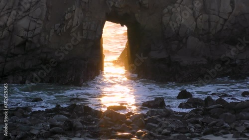 Sunshine glistened through the arch keyhole rock at Pfeiffer beach at Big Bur coastal beach photo