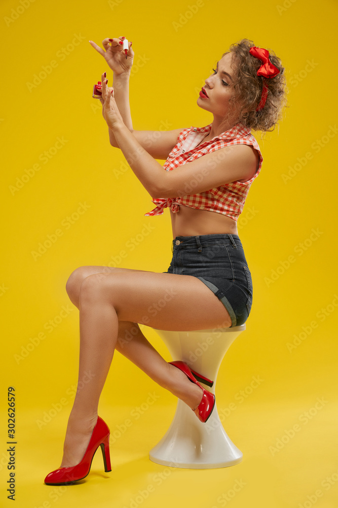 Glamour model with wavy hair painting nails by red lacquer Glamour model with wavy hair painting nails by red lacquer