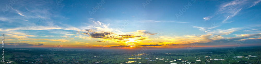 Panorama Top view Aerial photo from flying drone over village in Thailand.Cumulus sunset clouds with sun setting down on dark background.