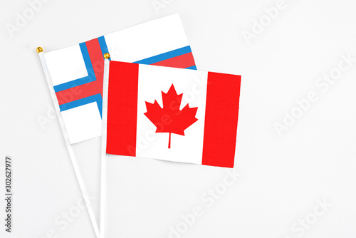 Canada and Faroe Islands stick flags on white background. High quality fabric, miniature national flag. Peaceful global concept.White floor for copy space.