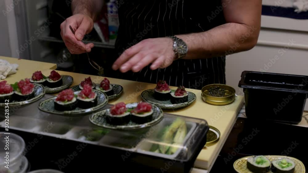 Sushi chef's work station, during preparation and plating of a fine dining sushi dinner. Close up on the delicate handwork. Sushi chef's work station, during preparation and plating of a fine dining sushi dinner. Close up on the delicate handwork.