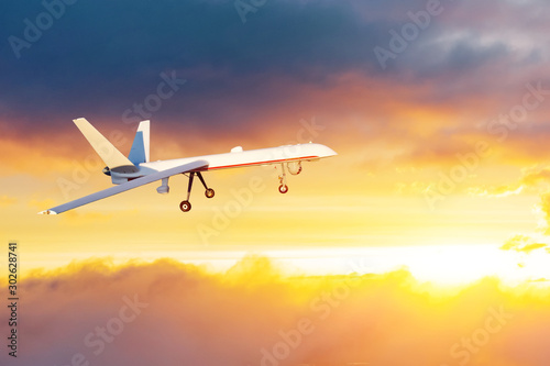Unmanned air vehicle remote piloted aircraft drone performing in sunset cloudscape panorama.
