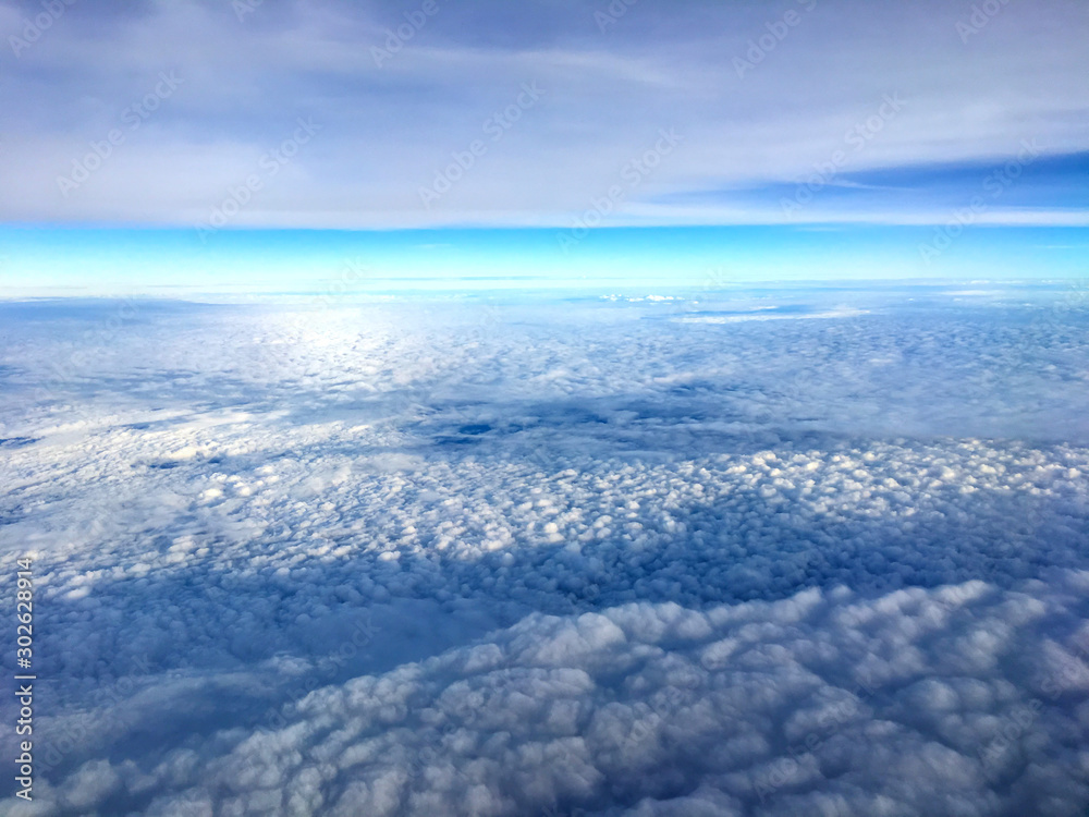 Clouds and sky as seen through window of an aircraft.Airplane wing in the blue sky above the clouds. Clouds and sky as seen through window of an aircraft.Airplane wing in the blue sky above the clouds.