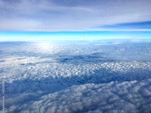 Clouds and sky as seen through window of an aircraft.Airplane wing in the blue sky above the clouds. © noon@photo