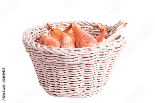shallots in a wicker basket on a white background