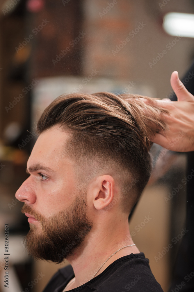 Fototapeta premium Fashionable man with a beard makes hair styling