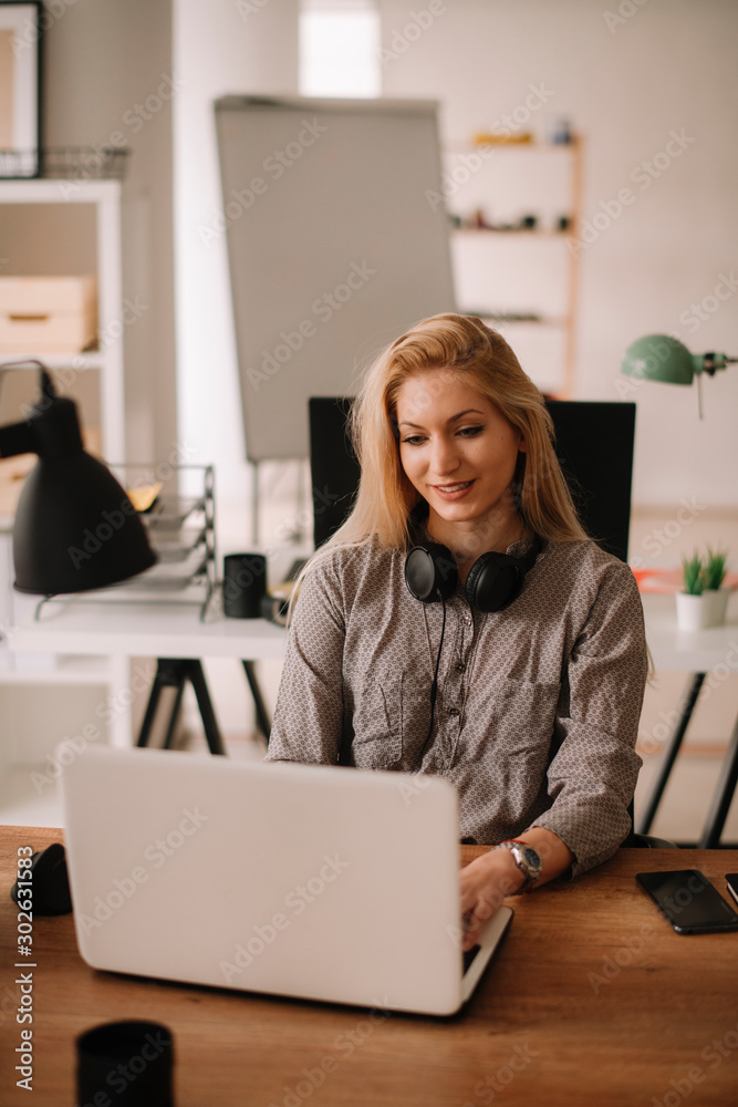 Young businesswoman in office. Beautiful woman with headphones. 